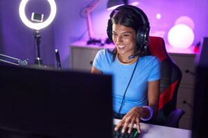 Brunette young woman playing video games looking positive and happy standing and smiling with a confident smile showing teeth