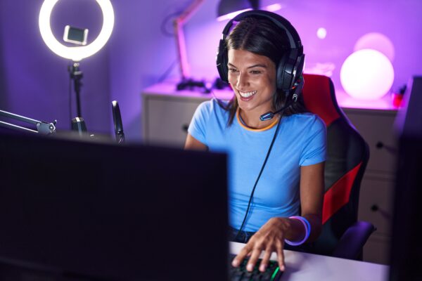 Brunette young woman playing video games looking positive and happy standing and smiling with a confident smile showing teeth